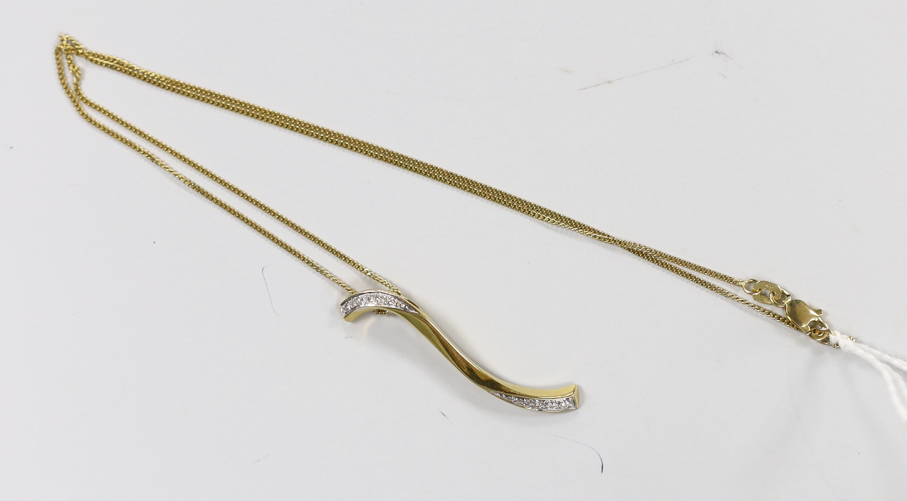 A modern 18ct gold and diamond chip 'S' shaped pendant, 38mm, on an 18ct gold chain, 39cm, gross weight 5.3 grams.